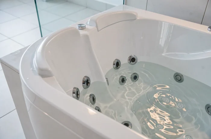 Détail des jets hydromassants et des appuis-tête ergonomiques d'une baignoire balnéo deux places en acrylique blanc